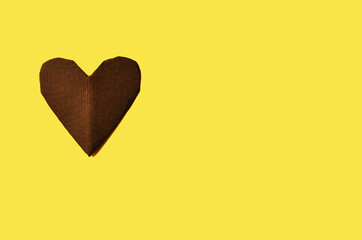 One heart carved from brown cardboard on a yellow background with a copy space. High quality photo