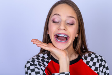 Teenager with smile shows white teeth with braces. white background.