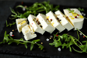 Soft focus. Fresh feta cheese on a black stone board.