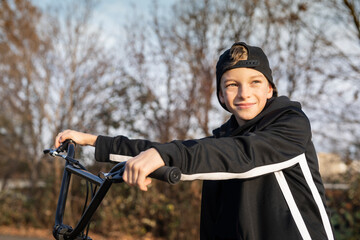 Junge mit schwarzen BMX-Fahrrad auf einem Sportplatz/Bahn. BMX-Räder sind das kleine Bike für...