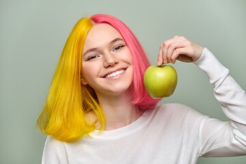 Head shot of beautiful smiling teenage girl with white smile with teeth, holding an apple