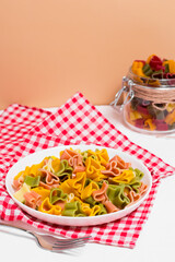 Ready-made Italian pasta with hearts in a white plate on a checkered white-red tablecloth. Valentine's day dinner.