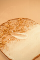 Cosmetic cream smear stroke texture. Epoxy resin gold colored round plates. Fine nudes, luxury minimalism. Sunlight, skin care product still life