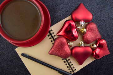 notebook for writing plans Christmas decorations hearts in the form of a Christmas tree and a red cup of coffee on a black background