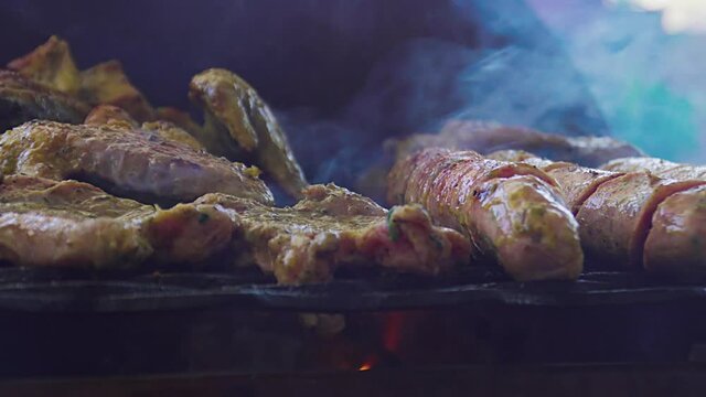 Unos deliciosos chorizos de chancho y pollo cubiertos de salsas y aceite vegetal  as&aacute;ndose en una parrilla cacera y grande en una casa de verano. Deliciosa comida. 