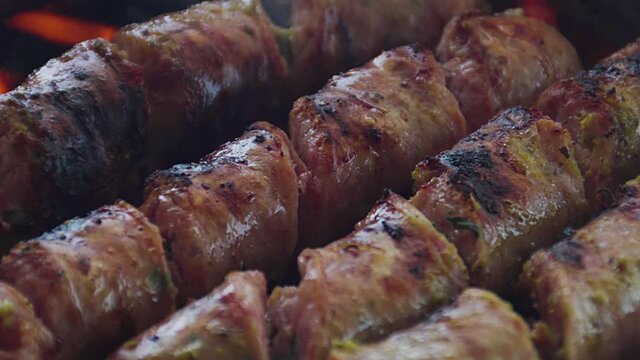 Unos deliciosos chorizos de chancho y pollo cubiertos de salsas y aceite vegetal  as&aacute;ndose en una parrilla cacera y grande en una casa de verano. Deliciosa comida. 