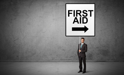 business person holding a traffic sign with FIRST AID inscription, new idea concept