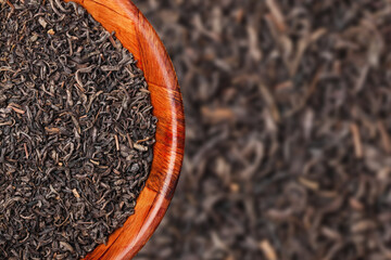 Black tea background. Empty copy space black tea in wooden bowl. Dry tea leaves texture.