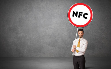 Young business person holdig traffic sign with NFC abbreviation, technology solution concept