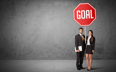 Young business person holding road sign with GOAL inscription, new rules concept