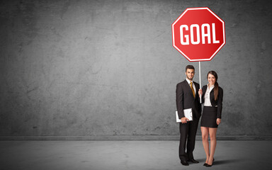 Fototapeta premium Young business person holding road sign with GOAL inscription, new rules concept