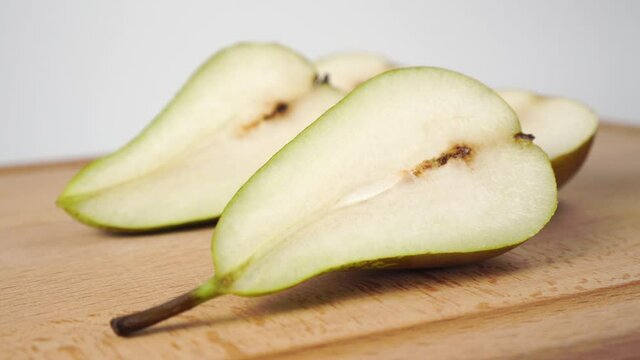 Sliced in half sweet juicy conference pear close-up on a wooden brown cutting board. Dolly Shot