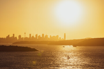 Beautiful evening sunset shot of the Sydney Harbour with the Sydney skyline in the background, seen from Fairfax Lookout at North Head Sanctuary. Shot in December 2020. Boats cruising in harbour.