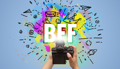 Close-up of a hand holding digital camera with abstract drawing and BFF inscription