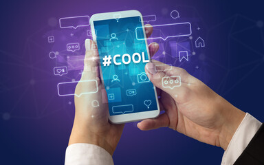 Female hand typing on smartphone with #COOL inscription, social media concept