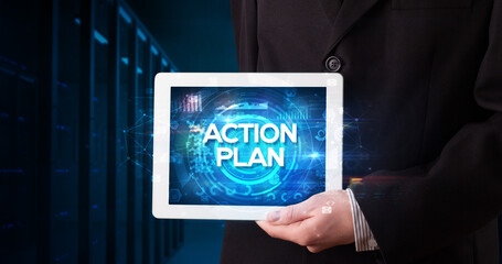 Young business person working on tablet and shows the inscription: ACTION PLAN, business concept