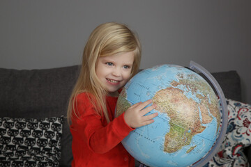 Portrait of adorable 3 years old girl playing with a globe.