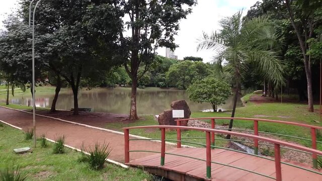 Drone voando sobre uma ponte, uma pedra e um lago, em dire&ccedil;&atilde;o a uma floresta