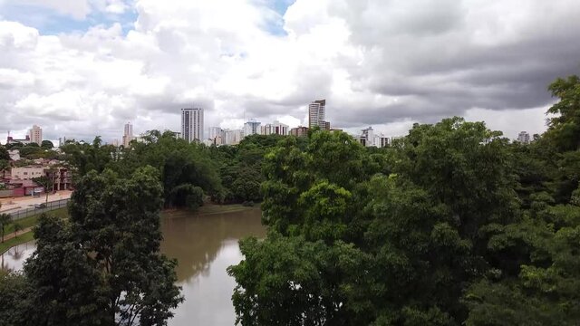 Drone voando para cima revelando a cidade atr&aacute;s da floresta