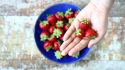 Soft focus. Fresh juicy strawberries in hand. The hand holds the bitten strawberry by the tail.