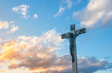 Jesus Christ on the cross against dramatic cloudy sky, at sunset. Crucifixion, religion and spirituality