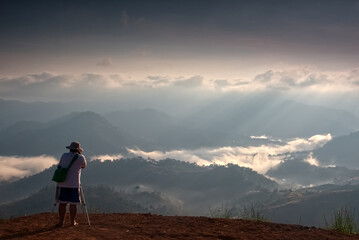 A photographer is taking a photo of  foggy mountain landscape in a morning, Thailand