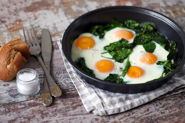 Eggs with spinach in a frying pan. Healthy breakfast. The keto diet.