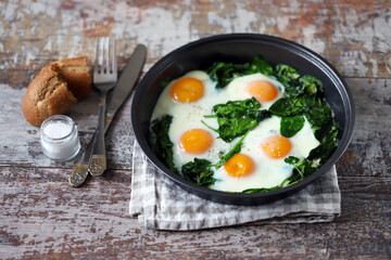 Eggs with spinach in a frying pan. Healthy breakfast. The keto diet.