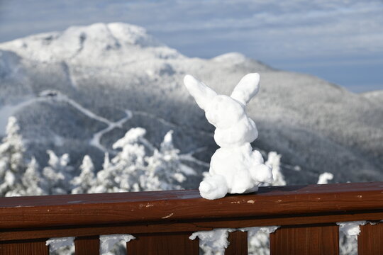 Ski bunny snow sculpture at Stowe Ski Resort in Vermont, view to the Mansfield mountain slopes, December fresh snow on trees early season in VT, panoramic hi-resolution image