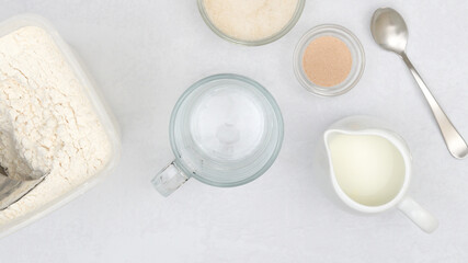 Dry yeast, milk, sugar, flour. Close up baking process, ingredients for baking needs on kitchen table
