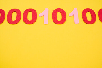 A top view of red and pink binary codes on a bright yellow surface