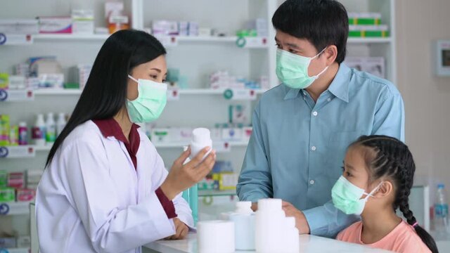 Asian Pharmacist in medical mask explaining the medication to patient in drug store