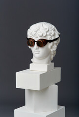 Plaster head of Antinous with round glasses. The concept of the absurd and the combination of the incongruous