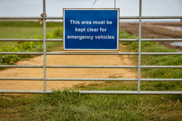 Sign: This area must be kept clear for emergency vehicles, seen on a closed gate in Thornham Old Harbour, Norfolk, England, UK