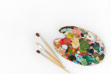 Artist's palette and brushes with different colors isolated on a white background