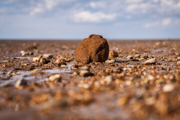A large stone surrounded by smaller stones in Snettisham Beach, Norfolk, England, UK
