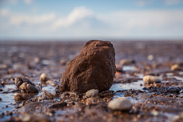 A large stone surrounded by smaller stones in Snettisham Beach, Norfolk, England, UK