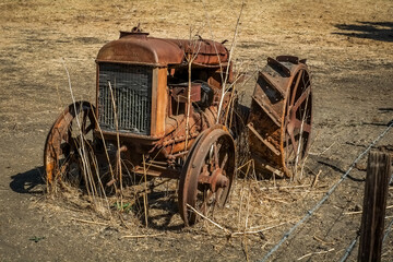 Historic Vintage rusty tractor in open hay field