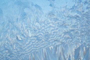 Winter frosty patterns on the window. Frozen glass texture. Abstract blue background.