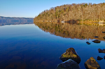 Fototapeta na wymiar 青空を湖面に映す冬の湖と湖畔の森