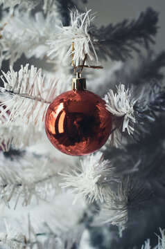 Bola decorativa roja en &aacute;rbol de navidad de color blanco.