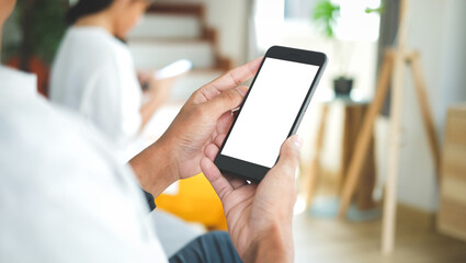 Close up view of male hands using smart phone with modern office blurred background. Blank screen monitor for graphic display montage.