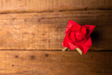 Red paper rose on an old wooden table with copy space. Selective focus. Concept for an ecological St Valentine's day