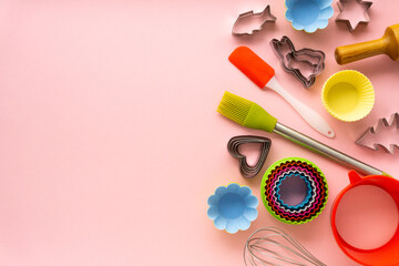 Flat lay of various baking utensils on pink background. Space for text