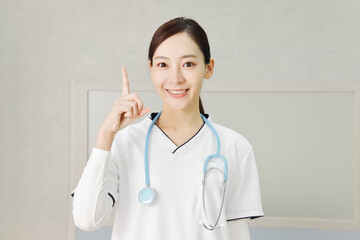 指差しポーズで笑顔の女性医師