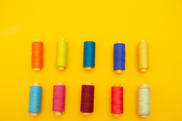 top view of Colored thread coils on yellow background, sewing, place for text
