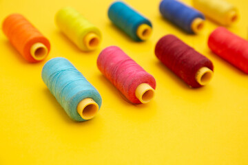 Color sewing threads on yellow background 