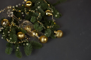 Space for new year greetings. fir branches, a glass and Christmas balls on the background of lights