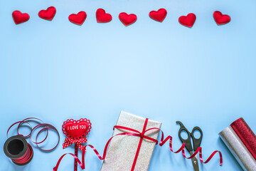 Valentine day creative layout with gift wrapping supplies and red fabric hearts