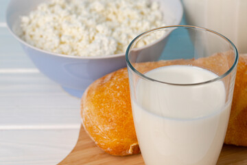 Glass of milk, bowl of cottage cheese and bread on table